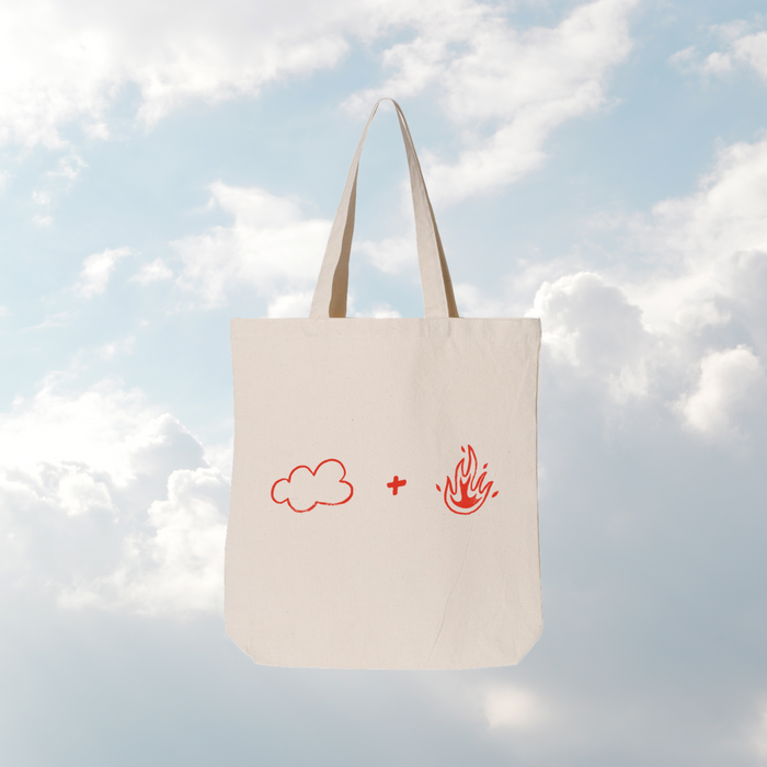 Tote bag with cloud and fire symbols against a cloudy sky background